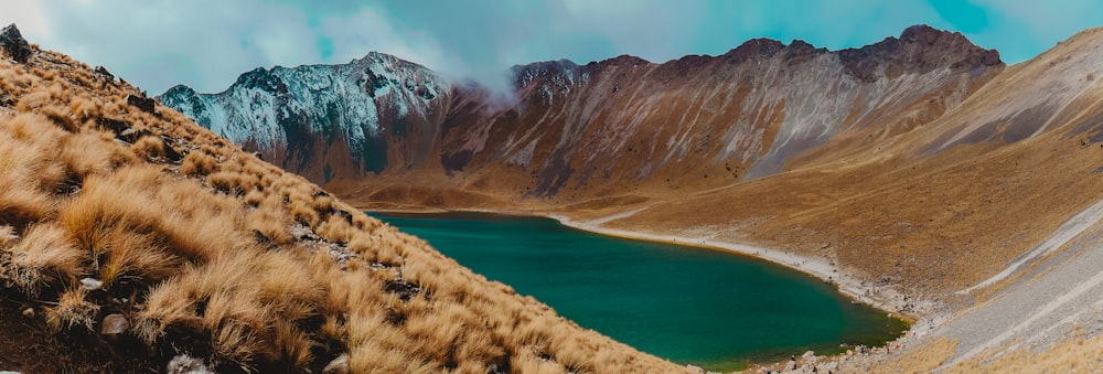 Montagna marrone e grigia vicino allo specchio d'acqua durante il giorno