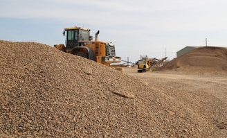 A robust dump truck unloading gravel at a busy construction site under clear blue skies.
