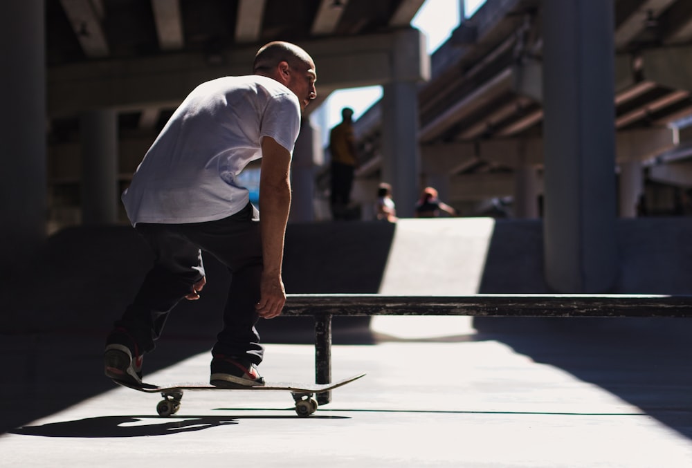 man in white t-shirt and black pants sitting on black metal bar