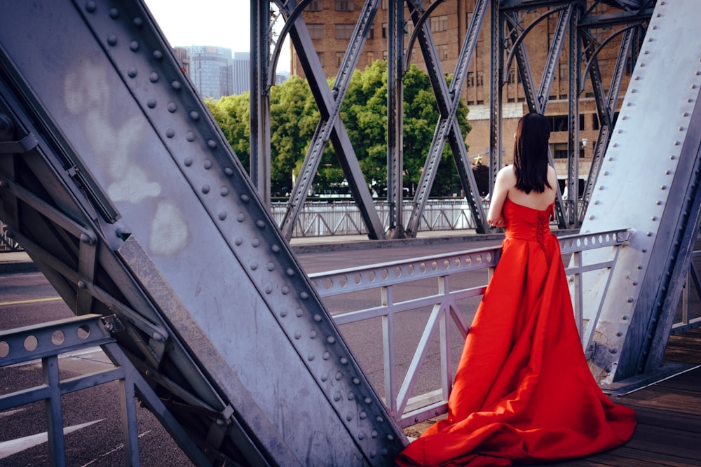 Frau in rotem Kleid steht auf Brücke