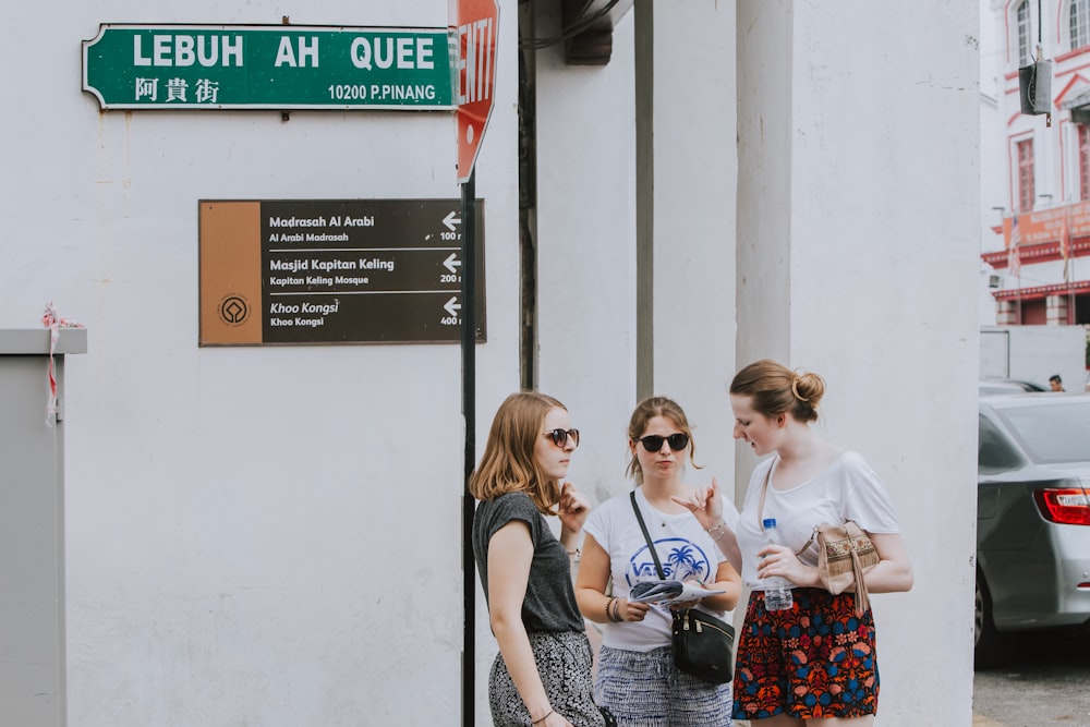 3 women standing beside white wall