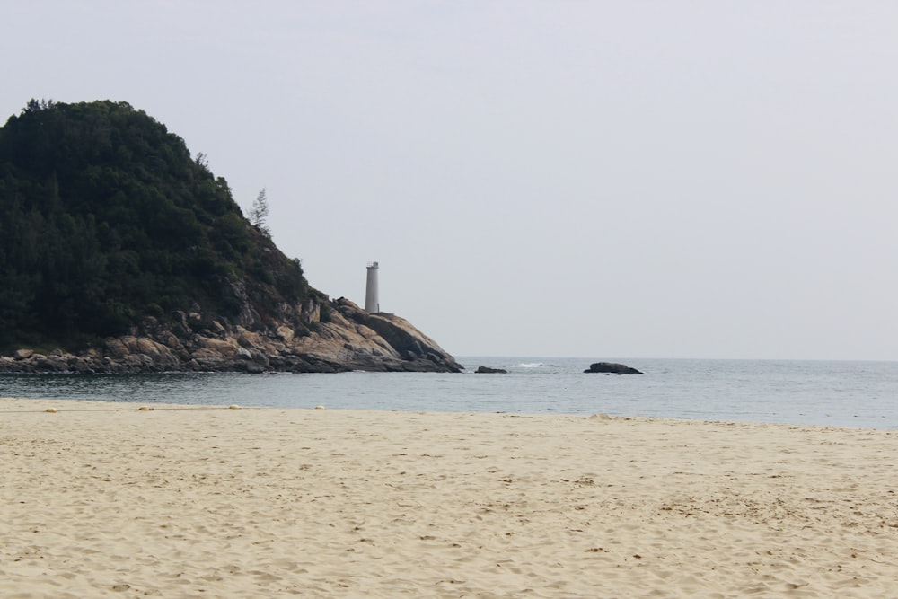 praia de areia branca com montanha verde à distância