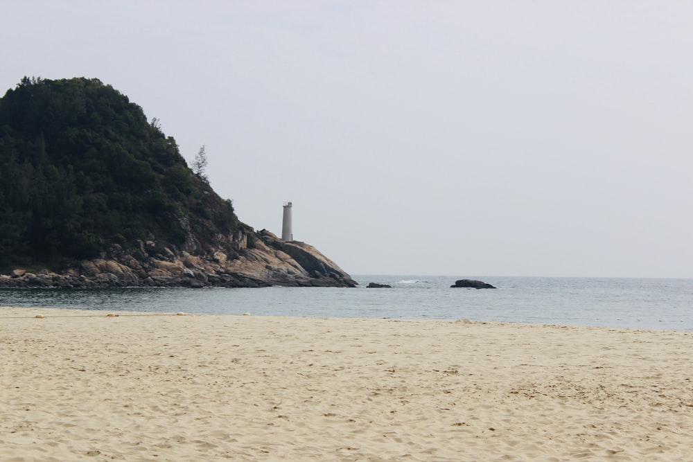 white sand beach with green mountain in distance