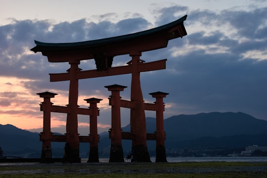 brown concrete building near body of water during daytime in Itsukushima Shrine Japan