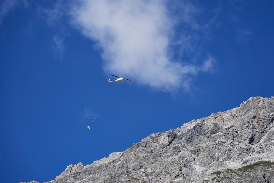 white and blue plane flying over rocky mountain during daytime