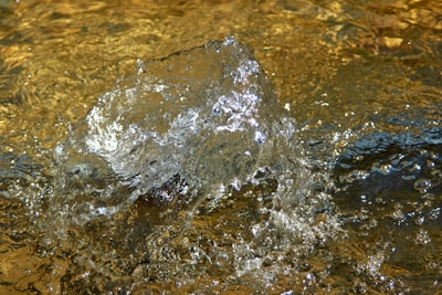 Close-up of shimmering gold dust overlaid on rippling water surface.