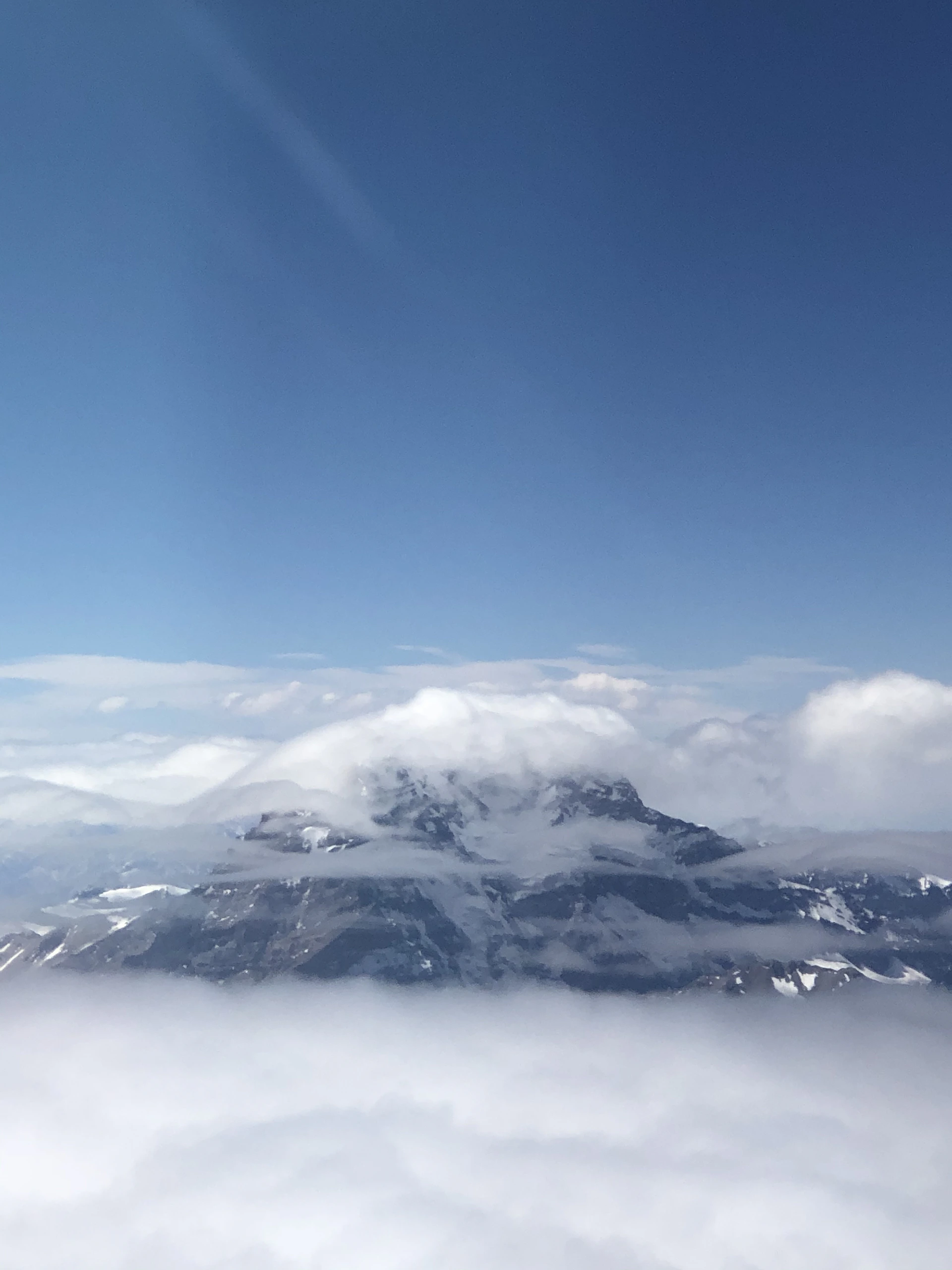 A majestic mountain peak rising above a sea of clouds under a clear blue sky, inviting adventure and exploration.