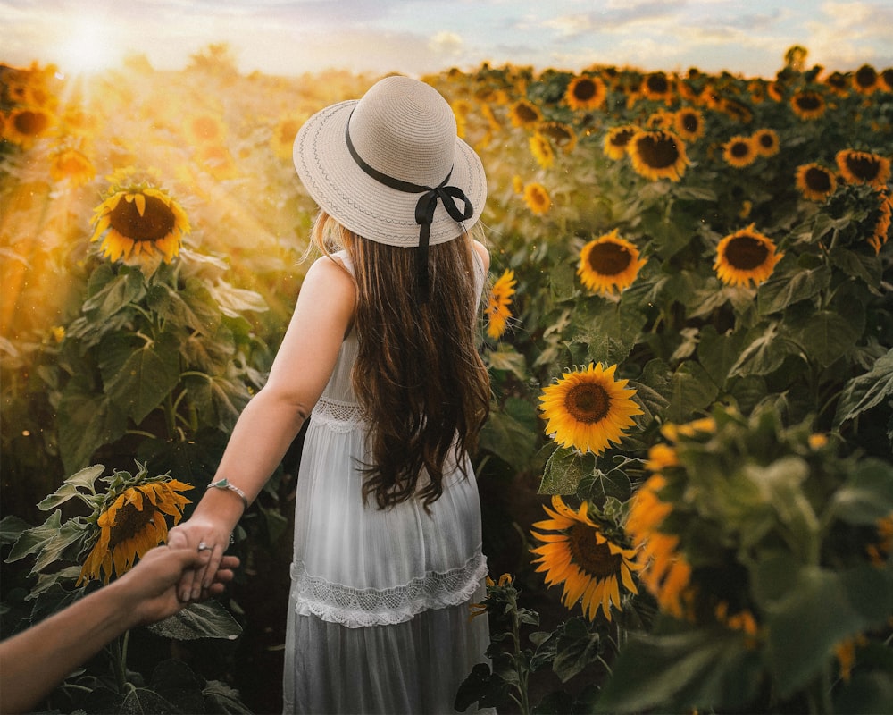 woman in white dress standing on sunflower field during daytime