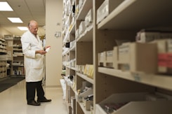 woman in white dress shirt and black pants standing near brown wooden shelf