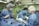 Medical professionals wearing surgical gowns and masks are engaged in a surgical procedure in an operating room. Various surgical instruments are neatly arranged on a blue surgical drape. Overhead surgical lights illuminate the scene, and medical equipment is visible in the background.
