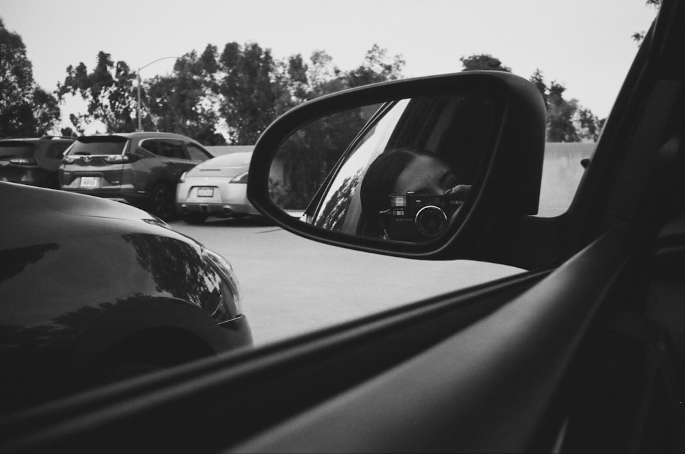Espejo lateral negro del automóvil que refleja los árboles durante el día