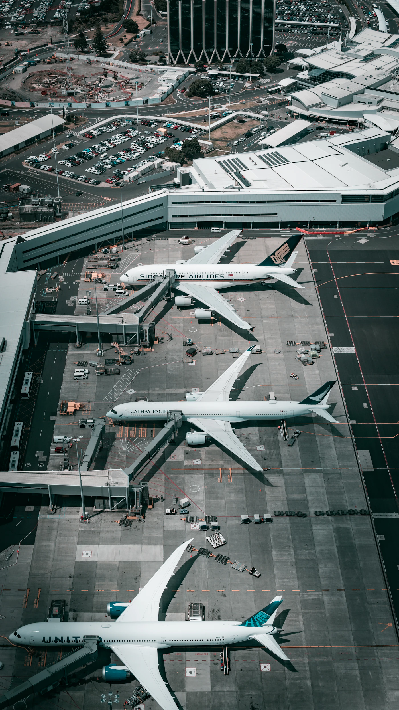 An overhead view of airliners parked nose-in at terminal gates with jet bridges connected, calm and ready before boarding