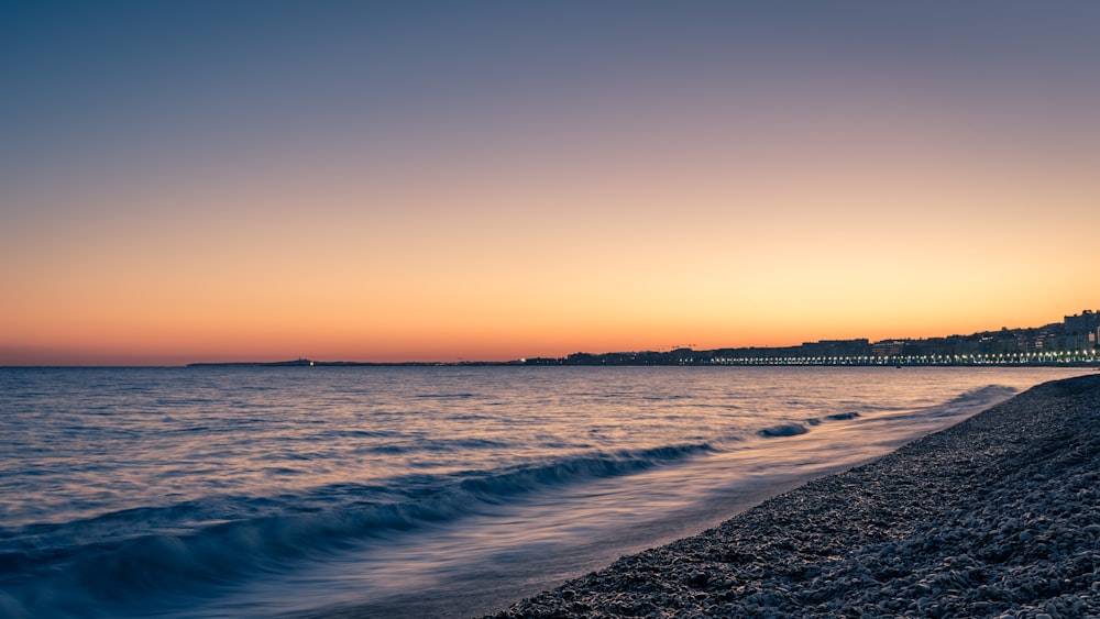 sea waves crashing on shore during sunset