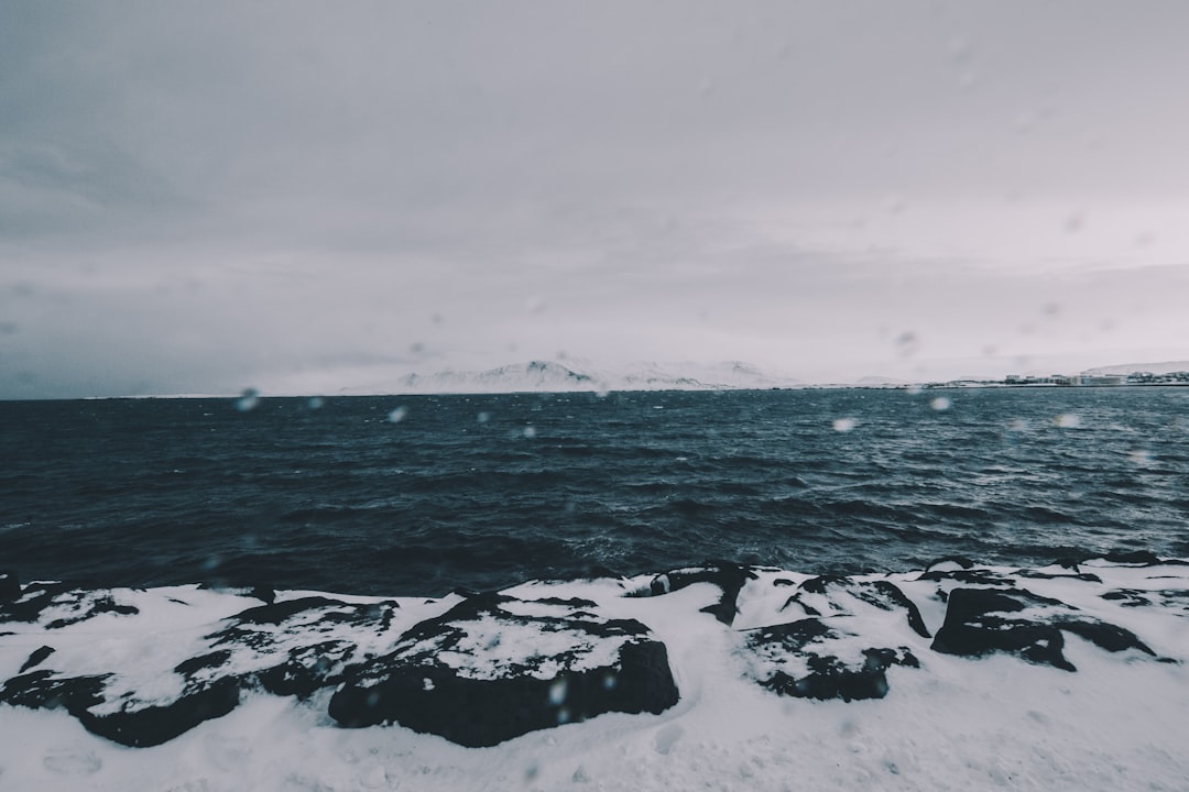 ocean waves crashing on rocks under white sky during daytime