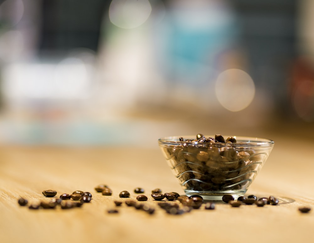 Tasse en verre transparent avec des grains de café sur une table brune