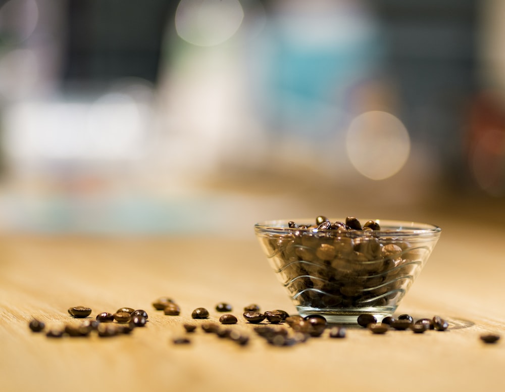 clear glass cup with coffee beans on brown table
