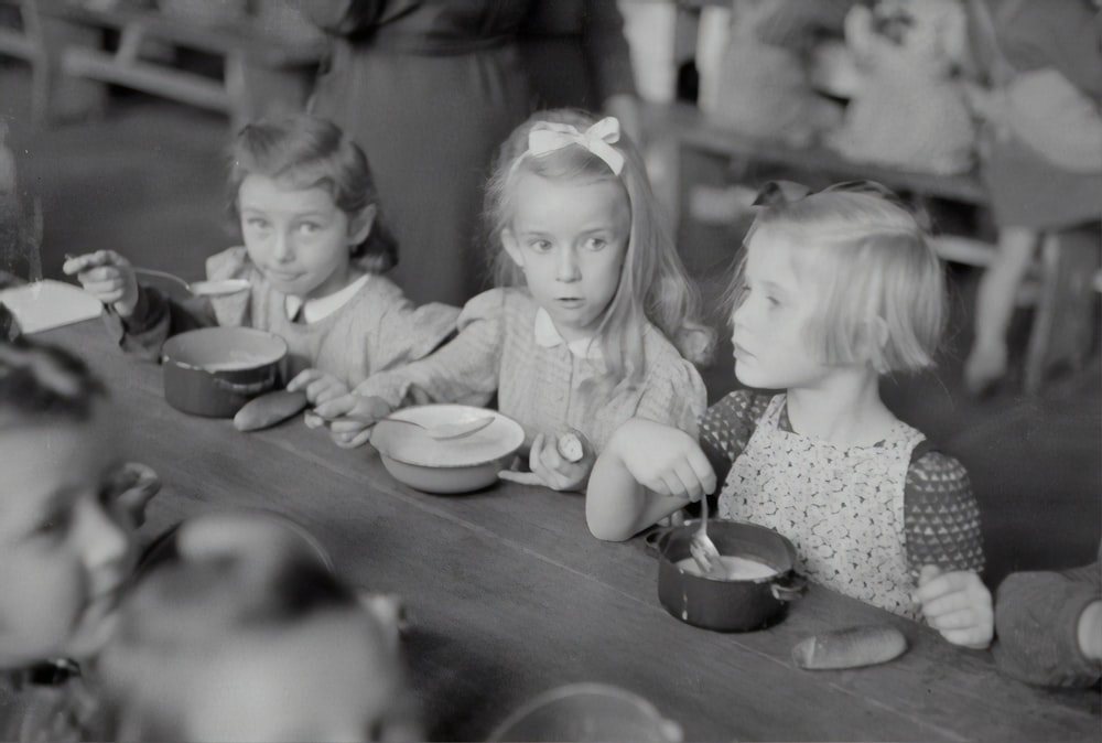 grayscale photo of 2 girls and boy sitting on chair