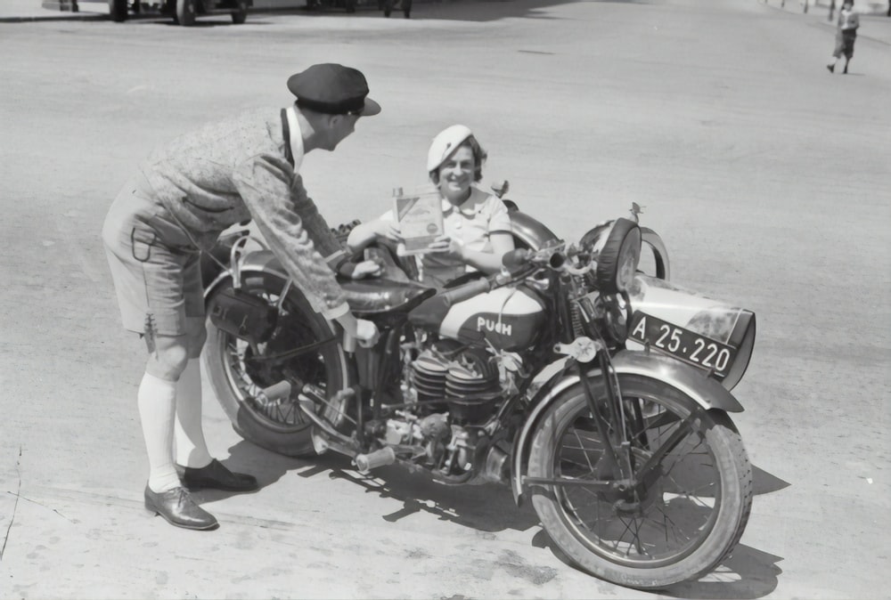 Mann in grauer Jacke und schwarzer Mütze fährt schwarzes Motorrad