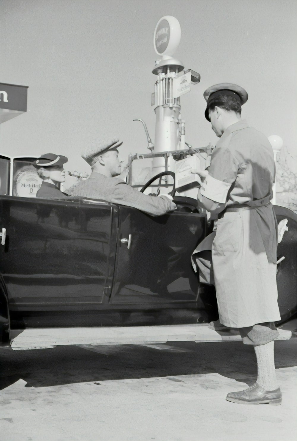 Hombre en uniforme blanco de pie junto a un coche negro