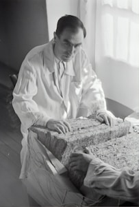 A building technologist examining composite materials in a cold storage facility surrounded by arid land.