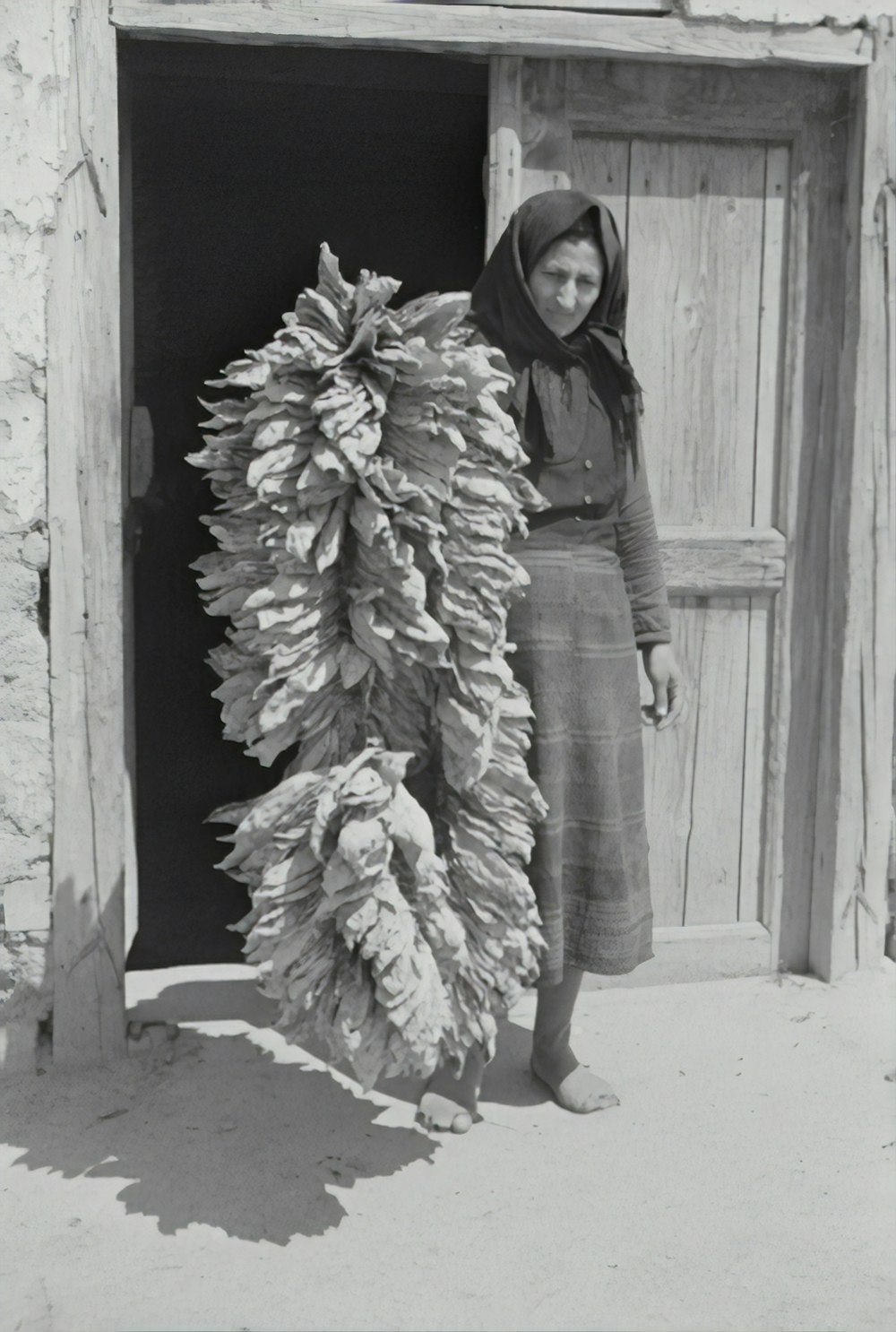 donna in giacca nera e gonna bianca in piedi accanto alla porta di legno
