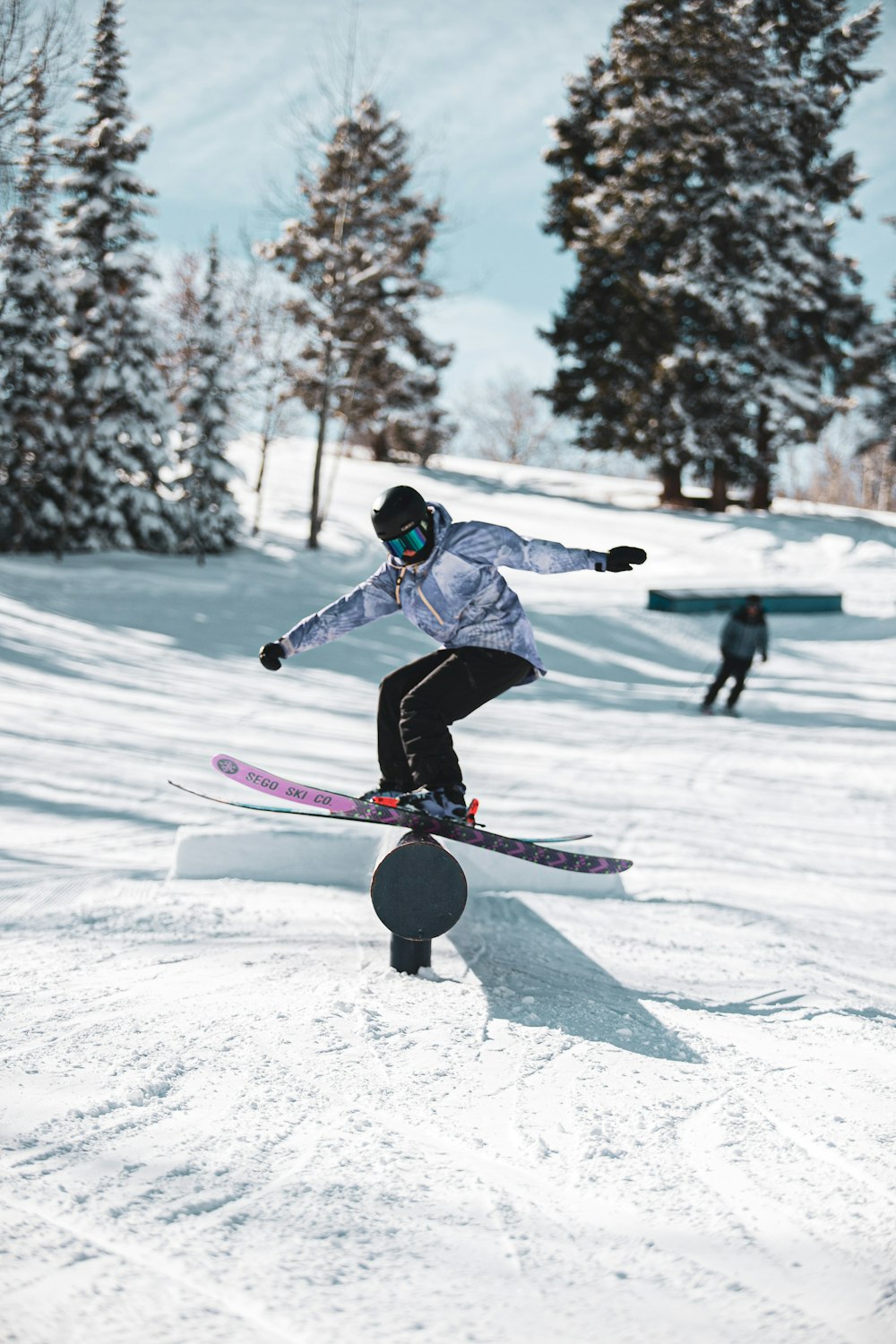 person in blue jacket and black pants riding on pink and white snowboard during daytime