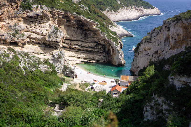 Stiniva cove on Vis, a pebble beach enclosed by tall limestone cliffs above clear water