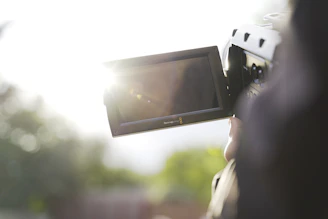 A creator filming a lively UGC video outdoors with natural sunlight highlighting their enthusiasm.