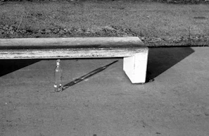 Minimalist dark grey display stand with a single cødex rełic bottle casting a long shadow