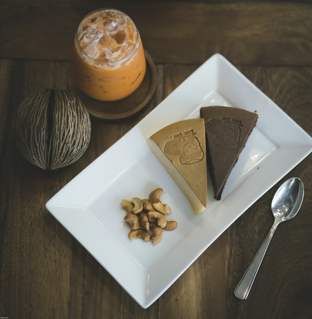 gâteau tranché sur assiette en céramique blanche à côté d’une cuillère en acier inoxydable