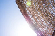 Close-up of textured wicker weaving on a poolside lounger catching the afternoon light.