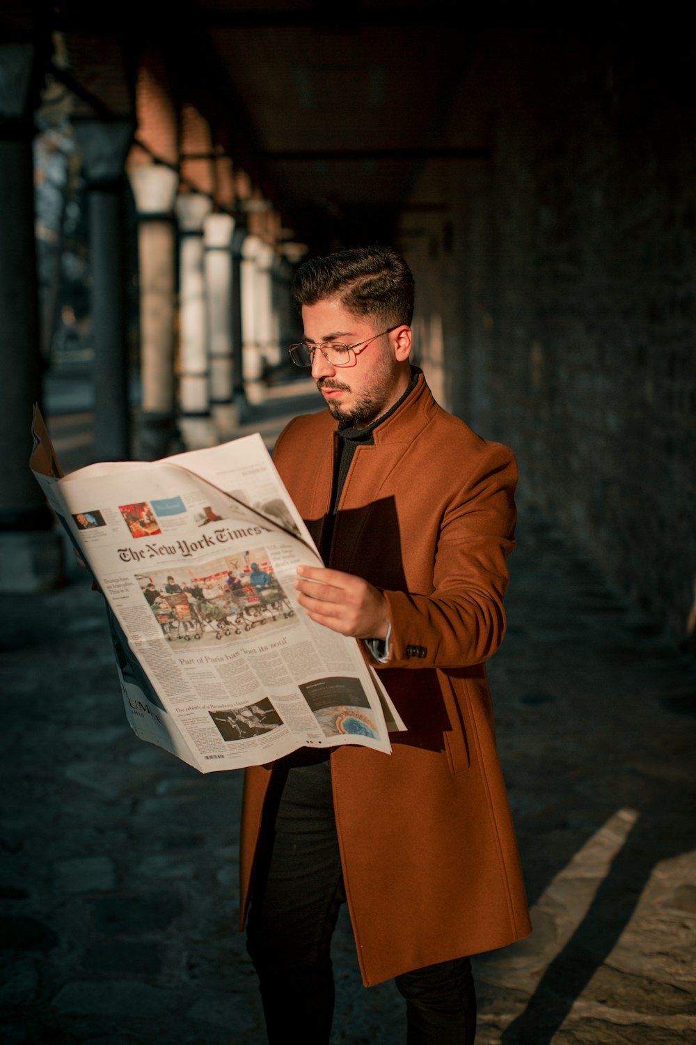 man in brown coat reading newspaper