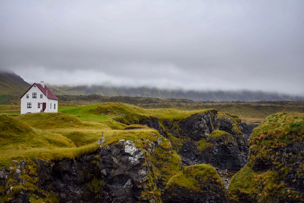 red and white house on green grass covered hill under white cloudy sky during daytime