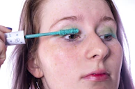 Model applying mascara with a bright smile, highlighting long, voluminous lashes
