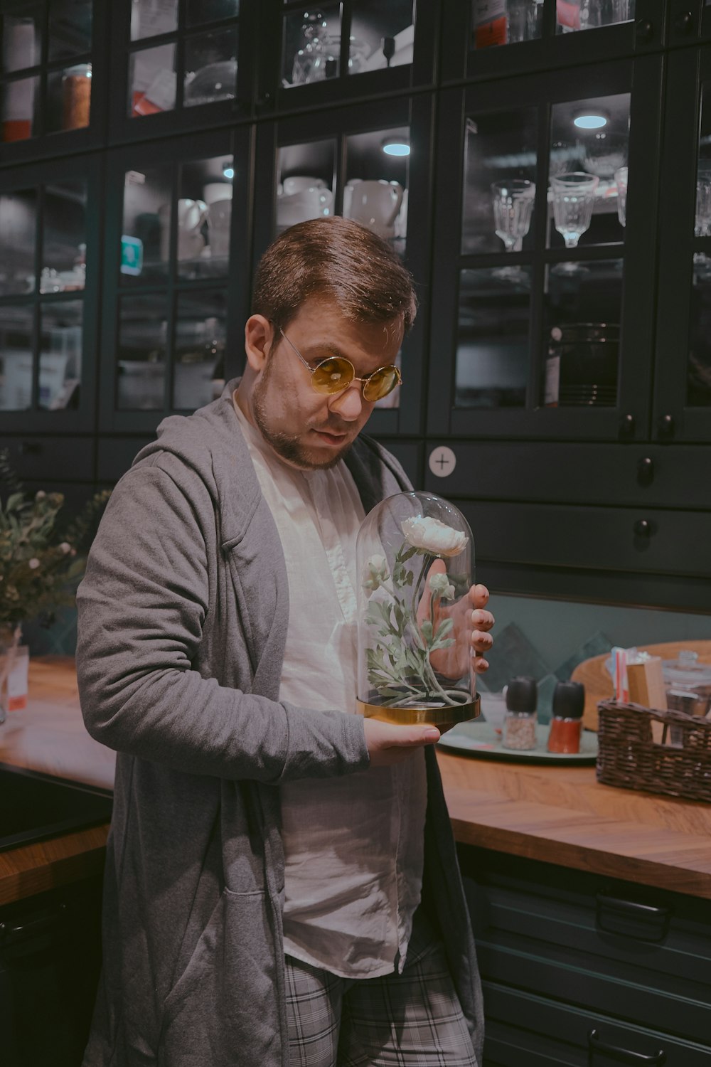 man in gray cardigan holding clear glass jar