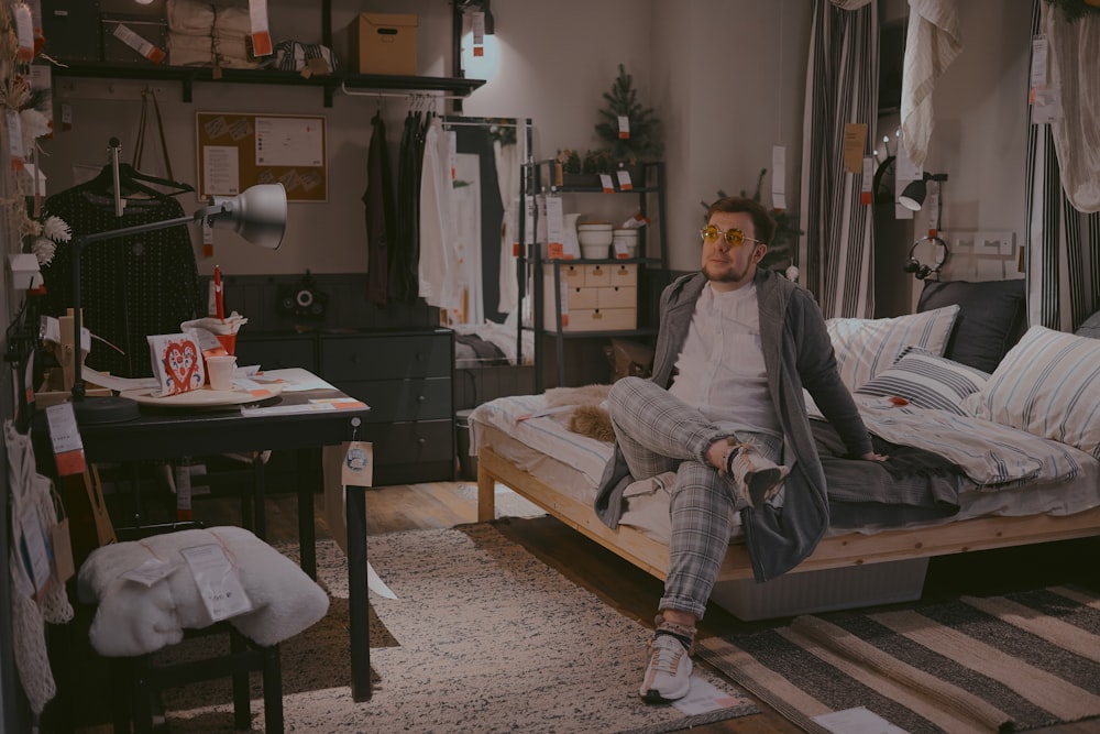 woman in gray jacket sitting on brown wooden bed