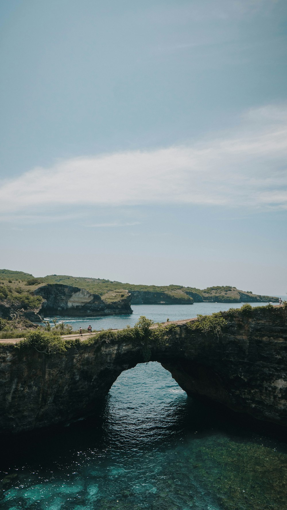 green and brown rock formation on body of water during daytime