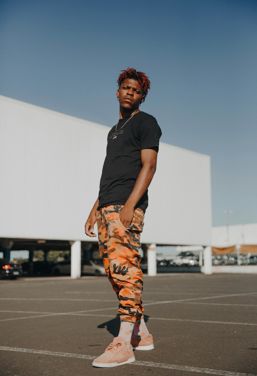 man in black t-shirt and brown pants standing on gray concrete floor during daytime