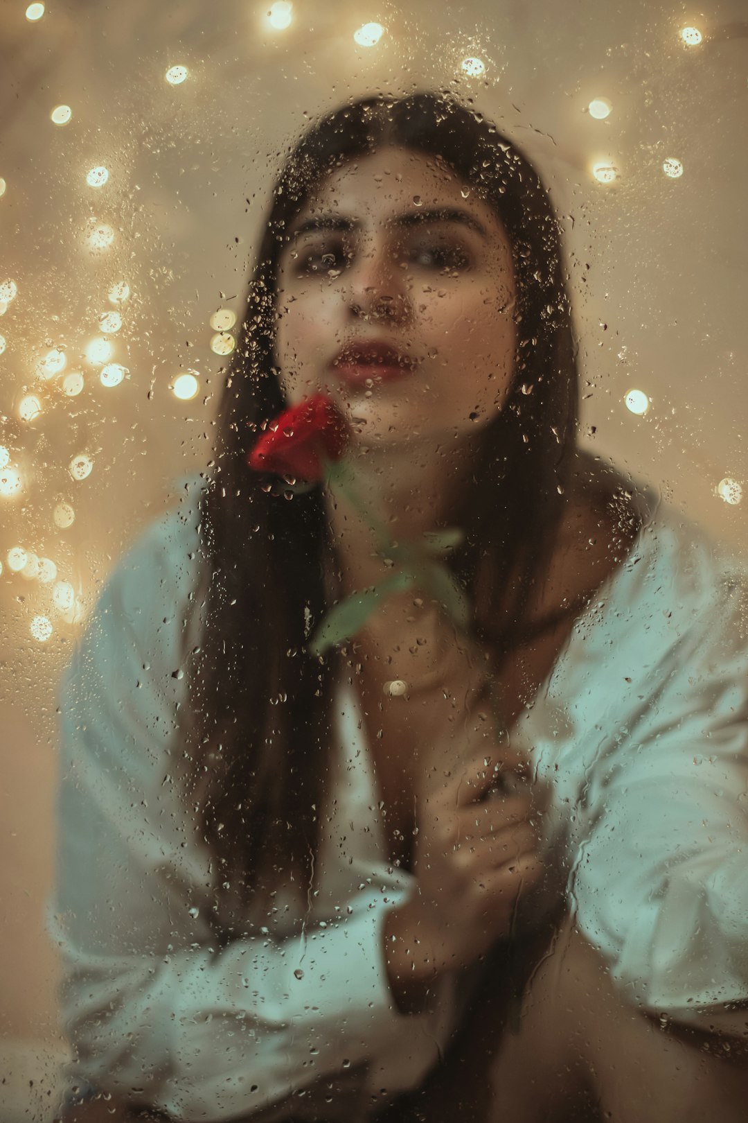 woman in teal long sleeve shirt holding red flower