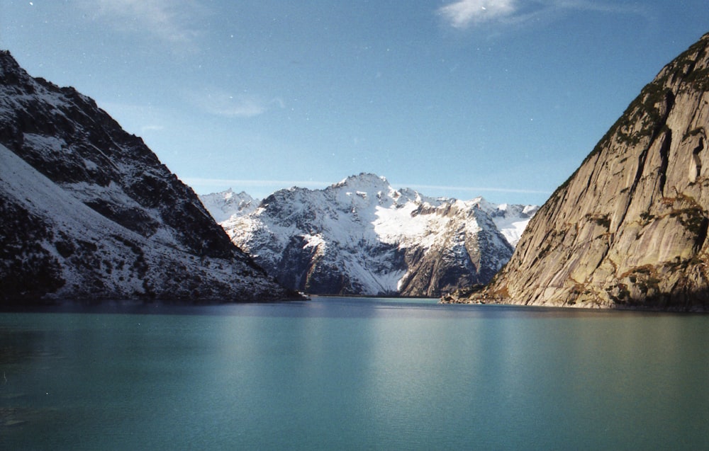 lake near snow covered mountains under blue sky during daytime