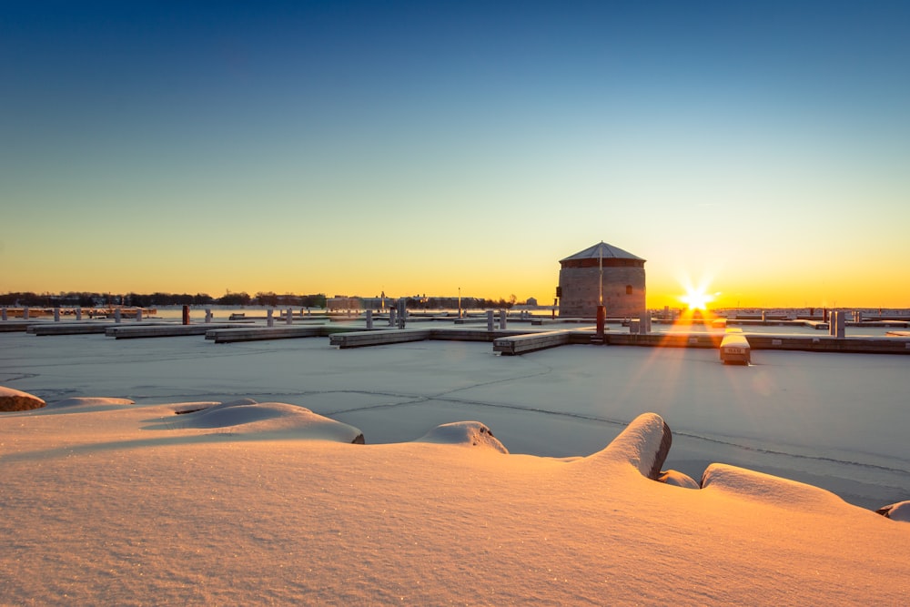 casa de madeira marrom no chão coberto de neve durante o pôr do sol