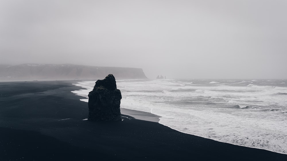 black rock formation on sea shore during daytime