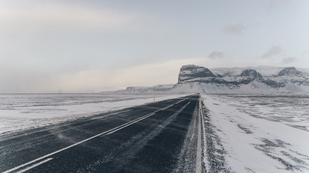 black asphalt road near snow covered mountain during daytime