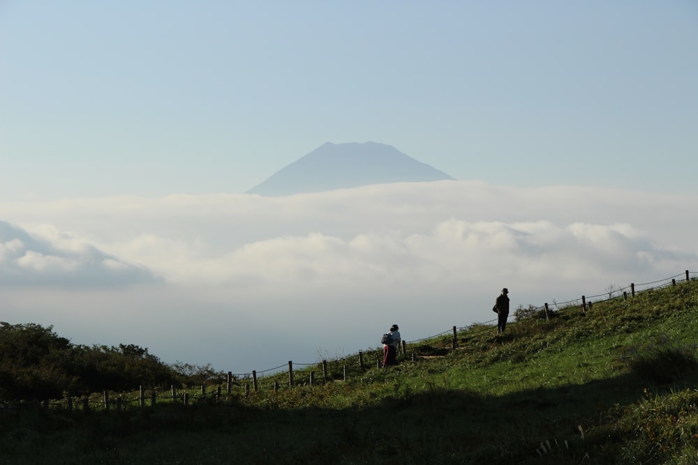 people walking on green grass field near mountain during daytime