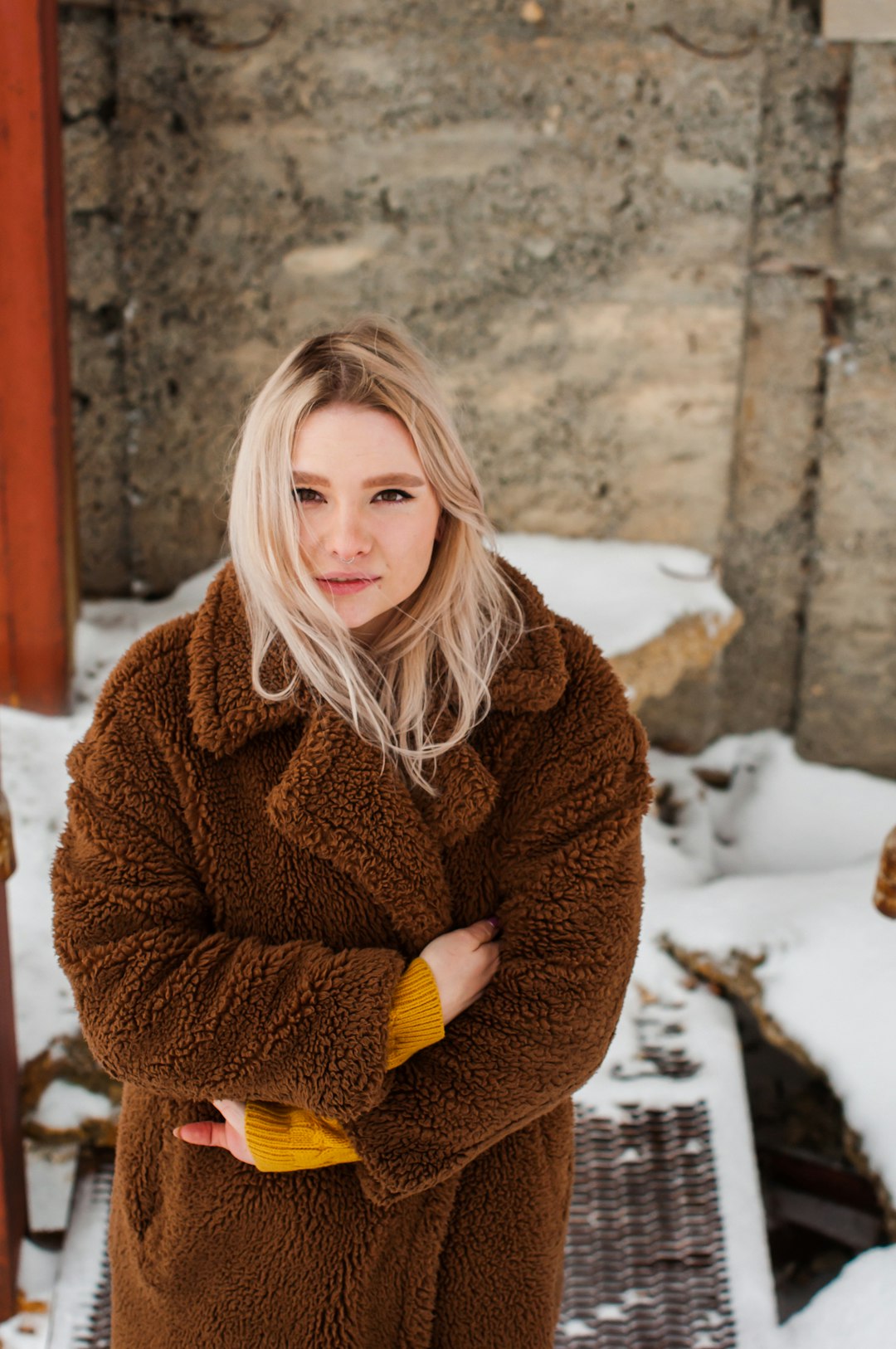 woman in brown fur coat standing on snow covered ground during daytime