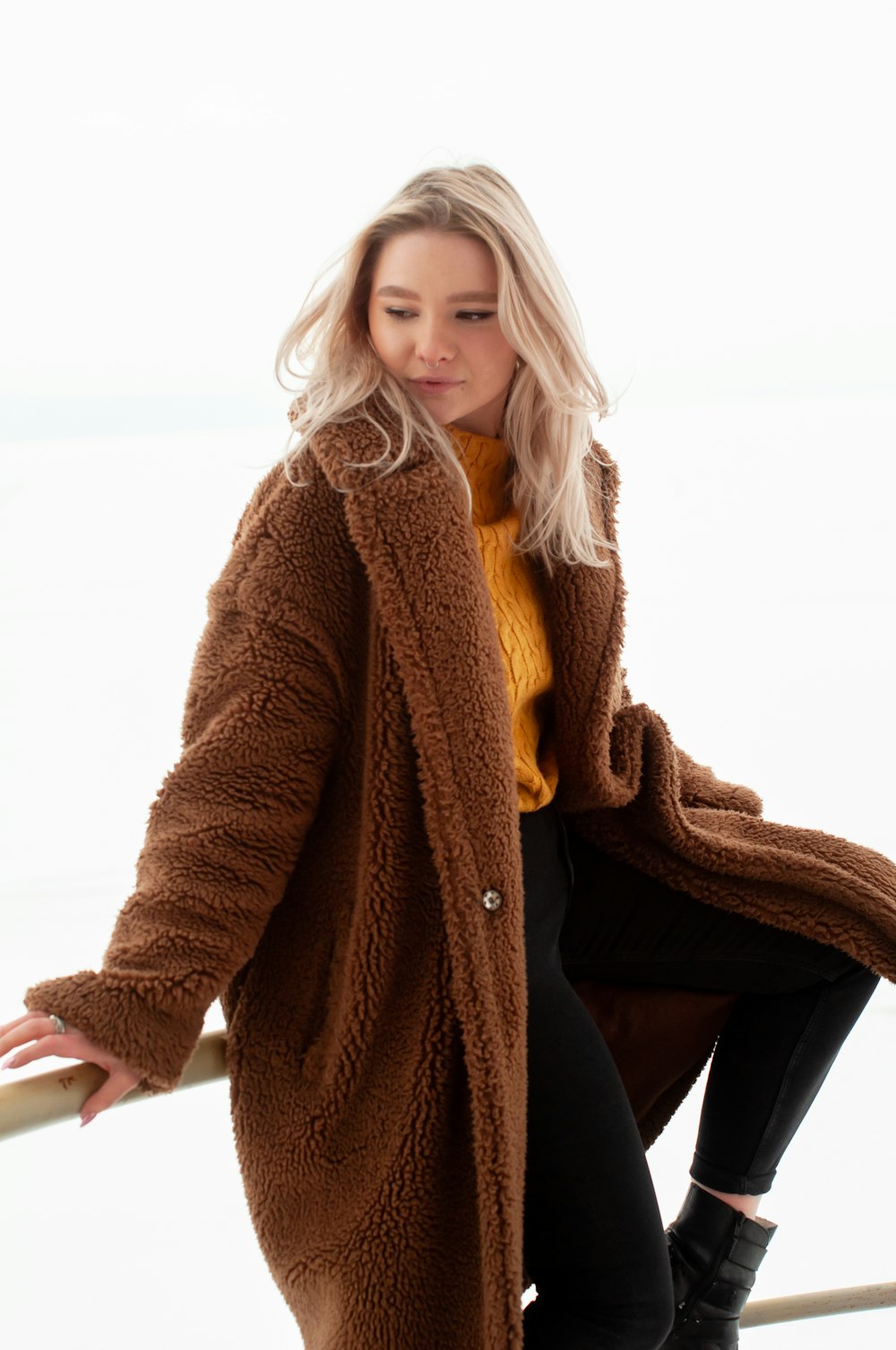 woman in brown coat sitting on white chair