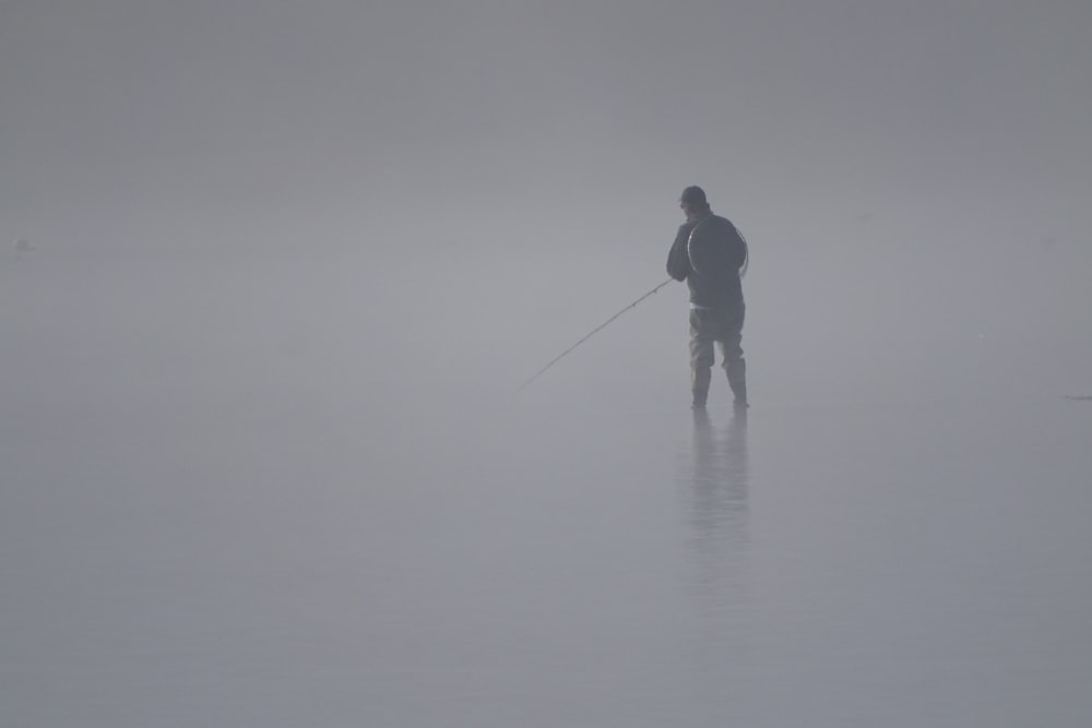 man in black jacket and pants fishing on sea