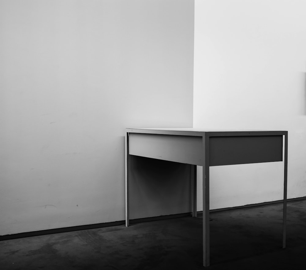 white wooden desk beside white wall