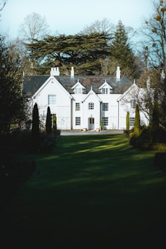 Elegant white and gold townhouse surrounded by lush greenery.