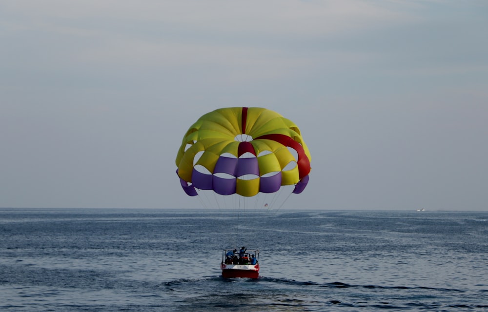 person in red and yellow parachute over sea during daytime